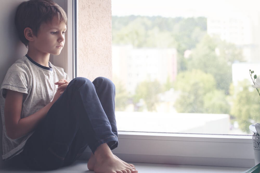 Sad-Kid-Sitting-on-Window-Shield-and-Looking-Out-the-Window